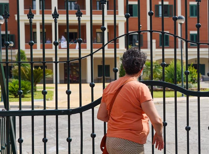 Una señora saluda desde la reja a un familiar en la residencia de ancianos de San Juan de Dios después de que la Junta de Andalucía permita visitar durante una hora a mayores en residencias. Sevilla a 02 de mayo del 2020