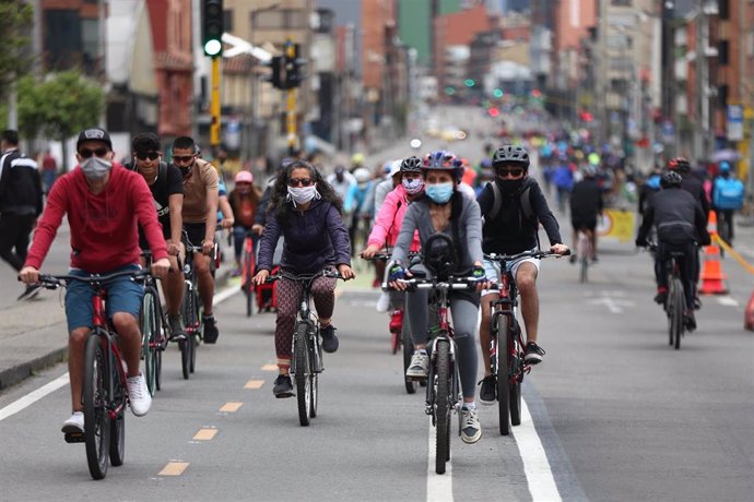 Personas con mascarilla van en bicicleta por una calle de Bogotá, Colombia. 