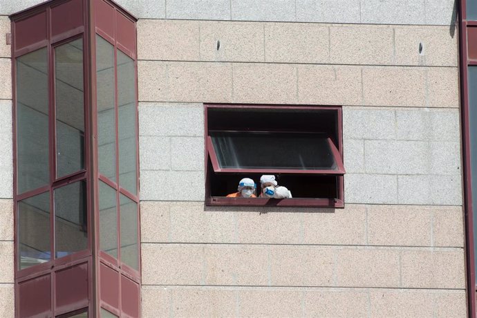 Dos trabajadores protegidos se asoman por una de las ventanas de la residencia de mayores DomusVi de Outeiro de Rei en Lugo, Galicia (España), a 8 de septiembre de 2020. La Xunta ha intervenido el geriátrico tras detectar 99 positivos más en covid-19, 9