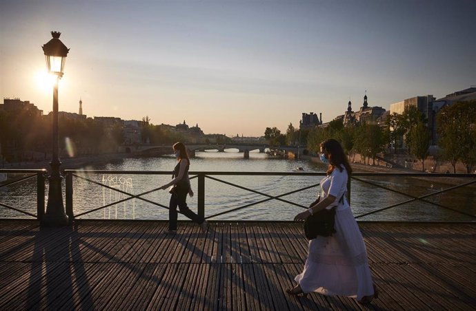 Personas con mascarilla sobre un puente del río Sena en París