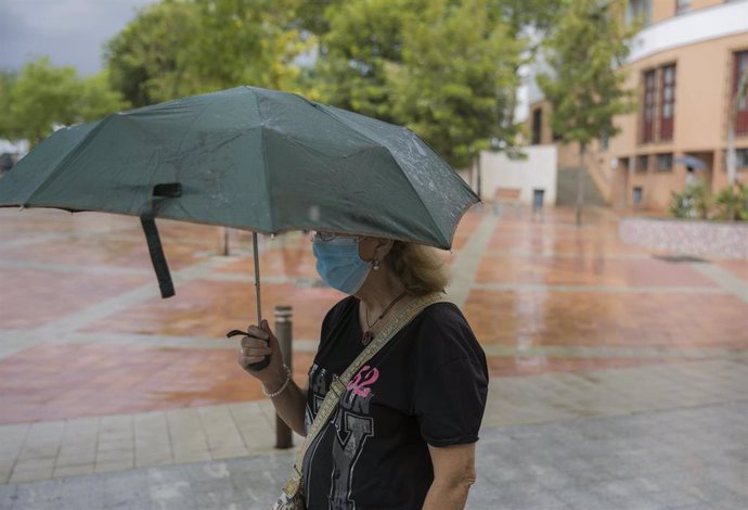 Una mujer se protege de la lluvia bajo su paraguas en Tomares (Sevilla, Andalucía, España), a 18 de septiembre de 2020.