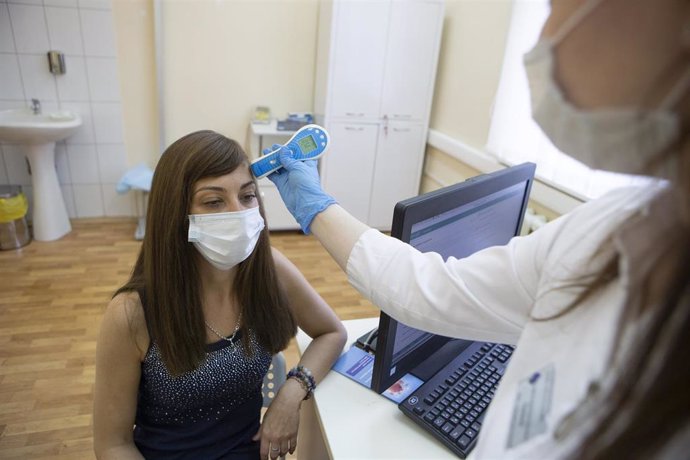 Una trabajadora sanitaria mide la temperatura de una voluntaria antes de aplicarle la vacuna rusa Sputnik V en la tercera fase de ensayos