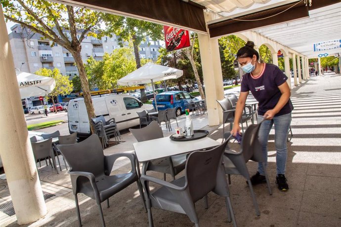 Una camarera limpia una de las mesas de la terraza del bar en el que trabaja
