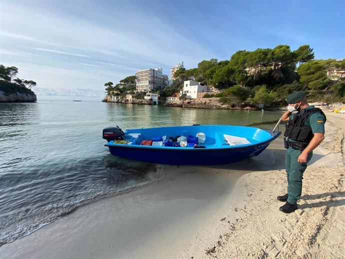Un agente de la guardia civil, junto a una embaración, en una playa de Baleares.