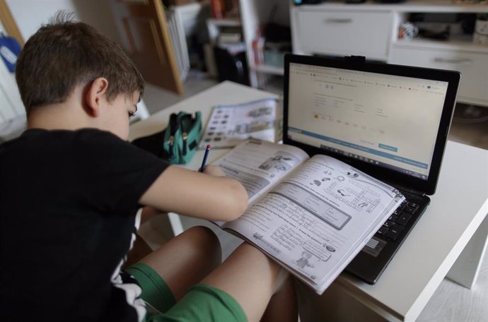 Un alumno de primaria hace los deberes de la asignatura de Inglés con varios libros y un ordenador a menos de un mes de terminar en casa el curso escolar 2019-2020 por la pandemia del Covid-19, en Madrid (España) a 20 de mayo de 2020.