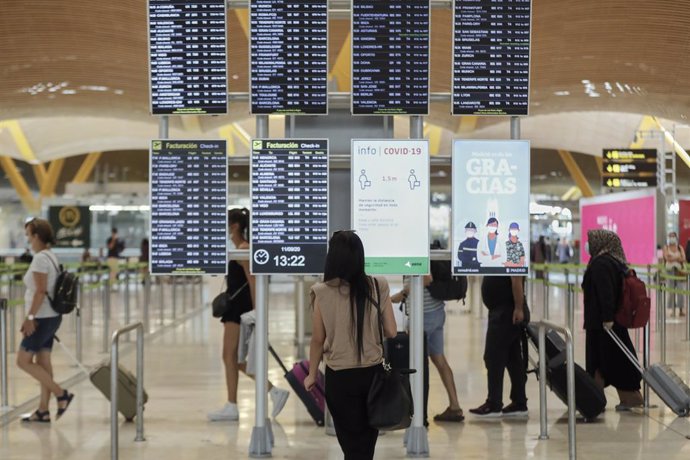 Pasajeros cerca de páneles informativos en la terminal T4 del aeropuerto Adolfo Suárez Madrid-Barajas, en Madrid (España)