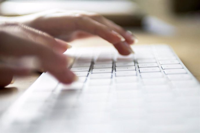 Una persona escribiendo en el teclado de un ordenador