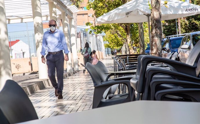 Una persona camina al costat d'una terrassa d'un bar buida del barri de Valdepasillas, pertanyent a la zona de salut de la Pau, una de les quals més contagis experimenta a Badajoz, Extremadura (Espanya), a 21 de setembre de 2020.