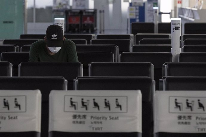 Un viajero con mascarilla espera en el aerpouerto de Haneda en Japón