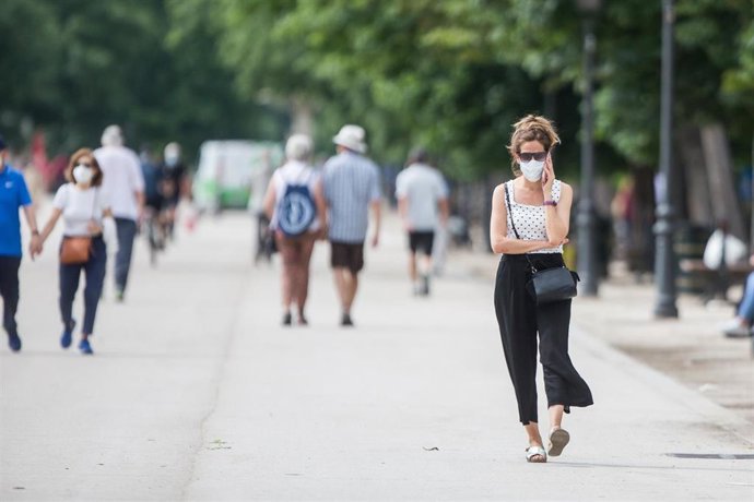 Varias personas pasean protegidas con mascarillas en el Parque de El Retiro.