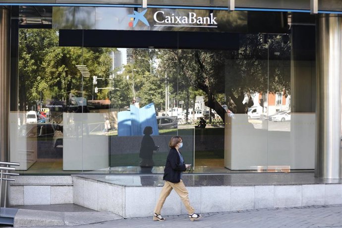 Una mujer pasa por al lado de las oficinas de Caixabank en el Paseo Castellana, en Madrid (España) a 4 de septiembre de 2020. CaixaBank y Bankia estudian emprender un proceso de fusión con el fin de aumentar su rentabilidad ante la crisis provocada por 