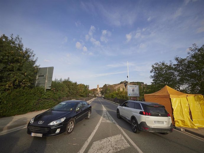 Dos vehículos circulan por la carrera de entrada a la localidad de Peralta, en Navarra (España)