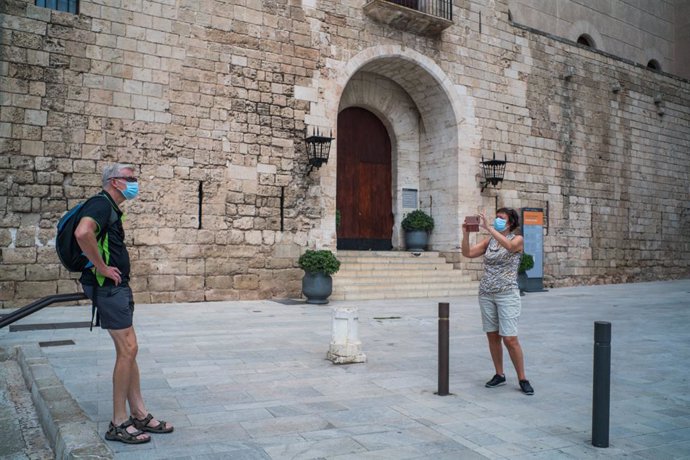 Dos turistas hacen una foto junto al Palacio de la Almudaina de Palma de Mallorca , Islas Baleares (España) a 13 de julio de 2020.  