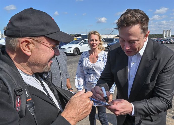 Elon musk firmando un autógrafo. 