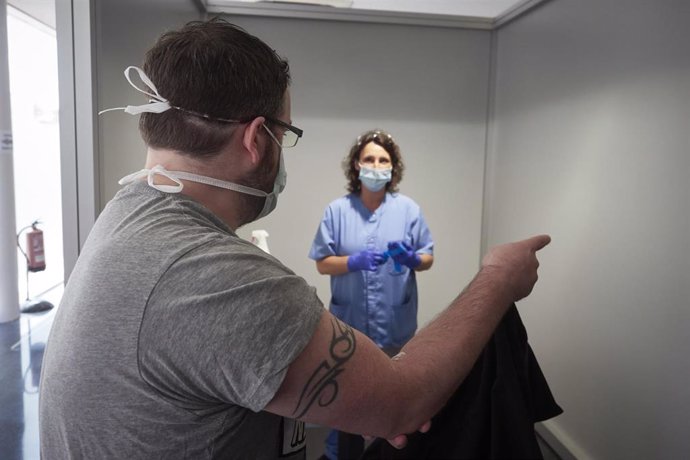 Una trabajadora atiende a uno de los pacientes que ha acudido para realizarse una extracción de muestras en el recinto ferial REFENA de Pamplona