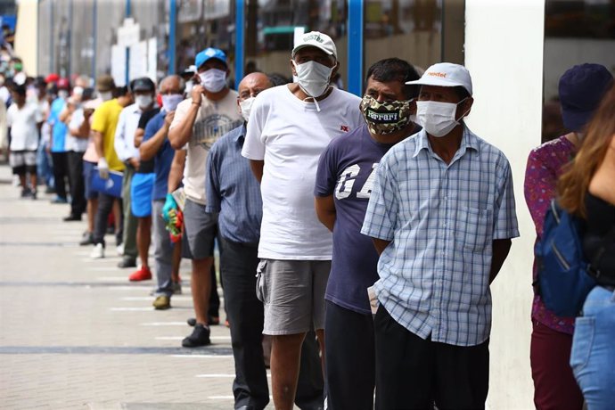 Un grupo de personas hace cola en una sucursal bancaria en un distrito de Lima para recibir el subsidio de 380 soles (90 euros) que otorga el Gobierno de Perú durante la crisis de la pandemia.