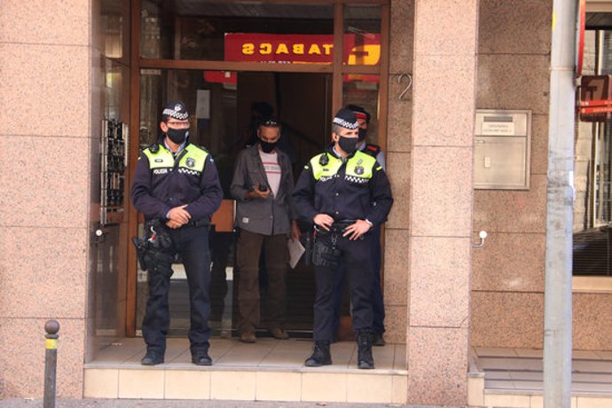 Pla mitj d'agents de la policia de Girona i dels Mossos a les portes de l'edifici on han trobat la dona aquest 26 de setembre del 2020. (Horitzontal)