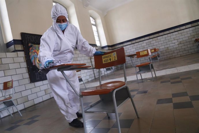 Una trabajadora desinfecta un pupitre en Bogotá por el coronavirus. 