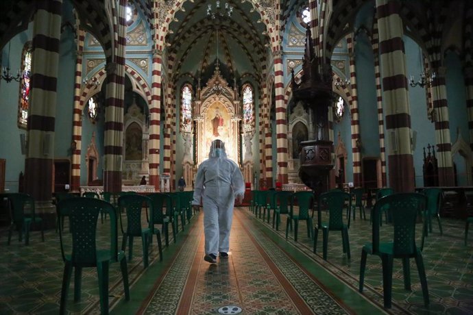 Un hombre ataviado con un  traje de protección camina por una iglesia de Bogotá, después de que en las últimas semanas se reabrieran los lugares de culto con ciertas restricciones a causa de la pandemia.