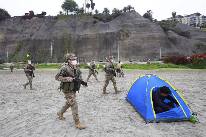 Un grupo de  soldados del ejército de Perú pide a los bañistas de las playas de la Costa Verde, en Lima, que abandonen  el lugar tras decretarse los cierres por la pandemia del coronavirus.
