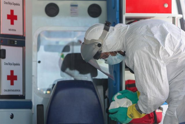 Un bombero limpia una ambulancia de Cruz Roja utilizada para trasladar enfermos de coronavirus, foto de archivo