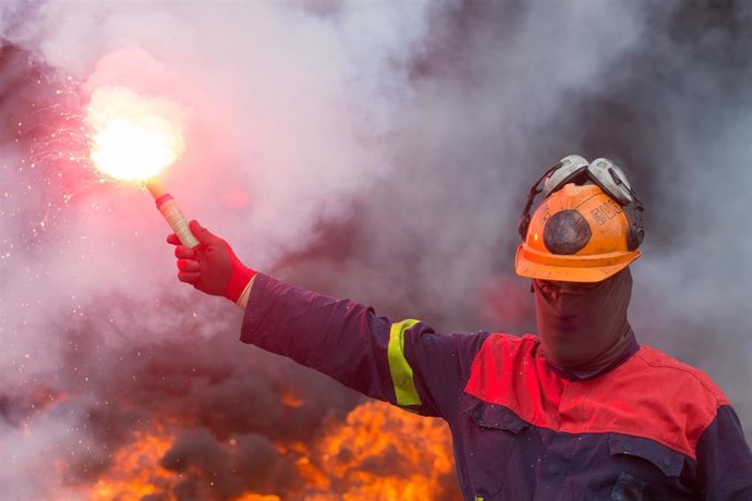 Un trabajador de Alcoa San Cibrao enciende una bengala durante una manifestación en la que han cortado la Autopista A6 con la quema de neumáticos, en Outeiro de Rei, Lugo, Galicia (España), a 22 de septiembre de 2020. 