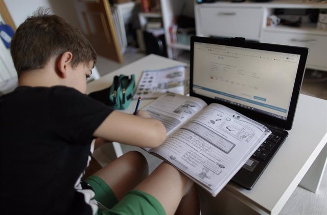 Un alumno de primaria hace los deberes de la asignatura de Inglés con varios libros y un ordenador a menos de un mes de terminar en casa el curso escolar 2019-2020 por la pandemia del Covid-19, en Madrid