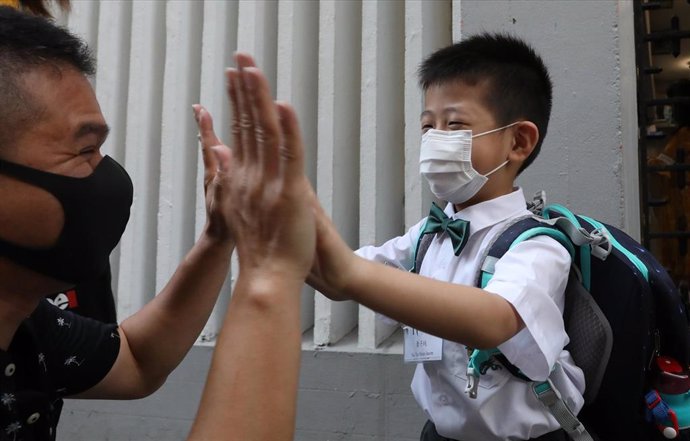 Un niño se despide de su padre antes de entrar a su escuela en Hong Kong.
