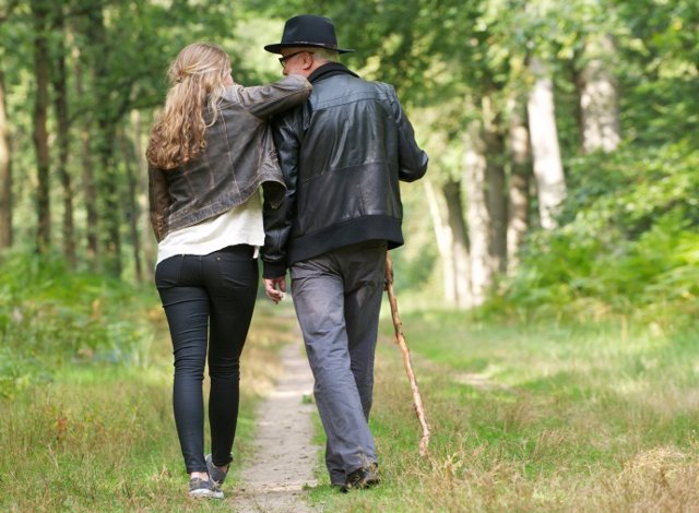 Padre e hija divirtiéndose al pasear por el bosque. 