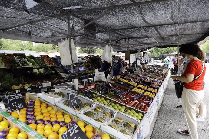Una mujer compra en un puesto de frutas en el mercadillo de Hortaleza (Madrid)