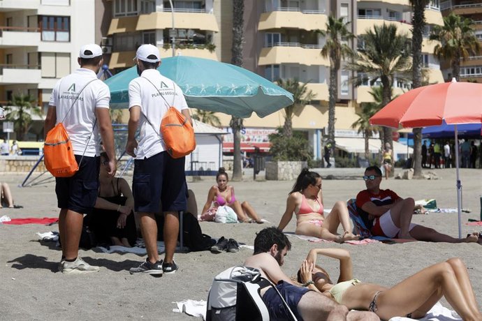 Una pareja de Vigilantes de la playa de Andalucía asesoran a bañistas sobre las medidas preventivas sobre el COVID-19 en la playa de La Malagueta.  En Málaga (Andalucía, España), a 19 de julio de 2020.
