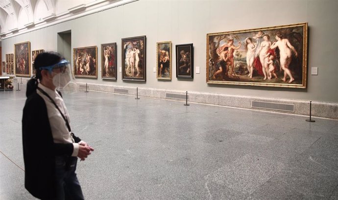 Una persona protegida con mascarilla observa una obra en el Museo del Prado