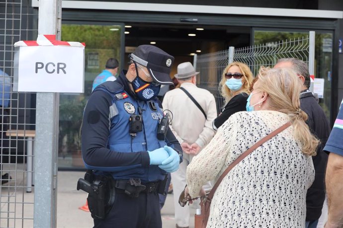 Un policía municipal pide la documentación a una mujer antes de entrar al Centro Cultural Lope de Vega, en la Zona Básica de Salud (ZBS) de Puente de Vallecas