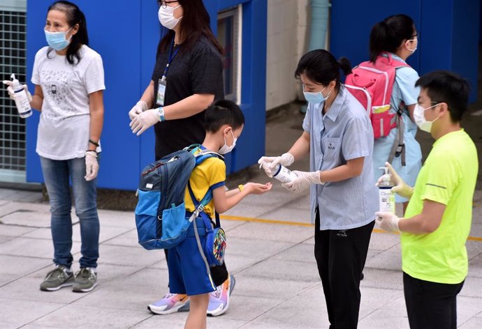 Un joven estudiante se aplica gel desinfectante antes de entrar a su centro escolar, situado en Hong Kong.