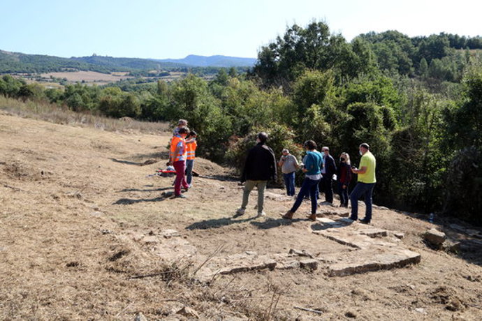 En primer pla restes de les parets de la casa residencial de la villa romana de Llorís i al fons els arquelegs explicant el jaciment el dia 30 de setembre del 2020. (horitzontal)