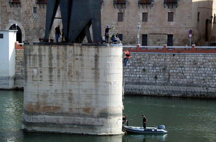 Pla general de la pilastra del monument franquista de l'Ebre de Tortosa amb els agents dels Mossos fent una inspecció ocular mentre un d'ells es despenja cap a l'embarcació. Imatge del 30 del setembre del 2020 (horitzontal)