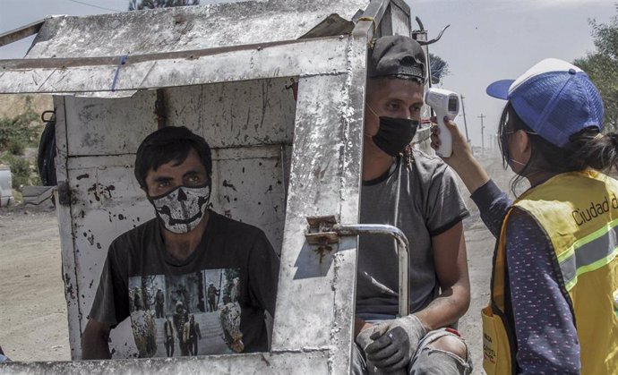 Toma de temperatura a dos trabajadores en un vertedero de México
