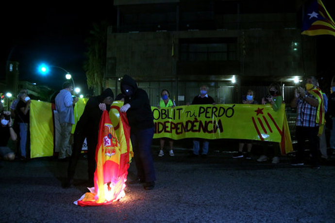 Pla obert de dos manifestants cremant una bandera espanyola al davant de la subdelegació del govern espanyol a Tarragona, l'1 d'octubre del 2020. (Horitzontal)