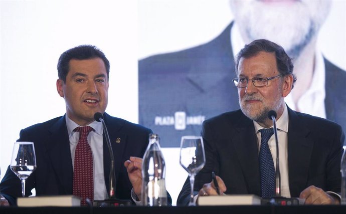 El presidente de la Junta, Juanma Moreno (i), durante la presentación del libro 'Una España mejor' del expresidente del Gobierno Mariano Rajoy (d). En Sevilla, a 20 de enero de 2020. (Foto de archivo).