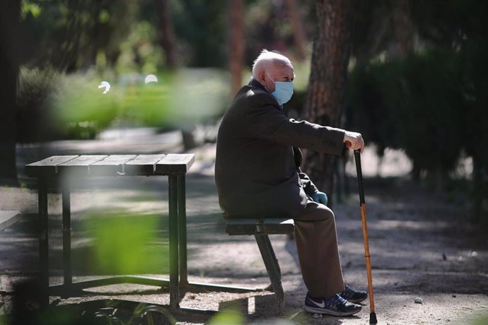 Un anciano con mascarilla descansa en el Parque Calero, en el distrito de Ciudad Lineal de la capital, uno de los que el Ayuntamiento de Madrid ha abierto y en los que se permite pasear y hacer ejercicio, en Madrid (España), a 8 de mayo de 20202.