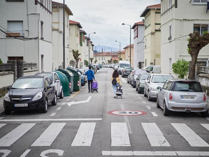 Dos personas con carros de la compra caminan por una calle de Pamplona.