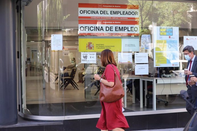 Una mujer con mascarilla pasa delante de una oficina de empleo en Madrid.