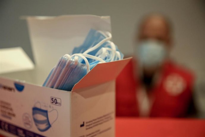 Un trabajador de Cruz Roja muestra las mascarillas que entregan a aquellos que necesiten