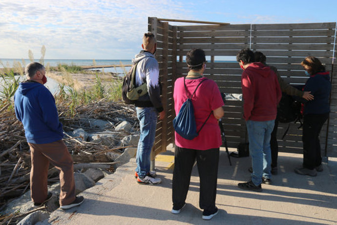 Un grup de participants a la visita guiada d'aquest diumenge 4 d'octubre de 2020 a Blanes explora ocells des d'un mirador. (Horitzontal)