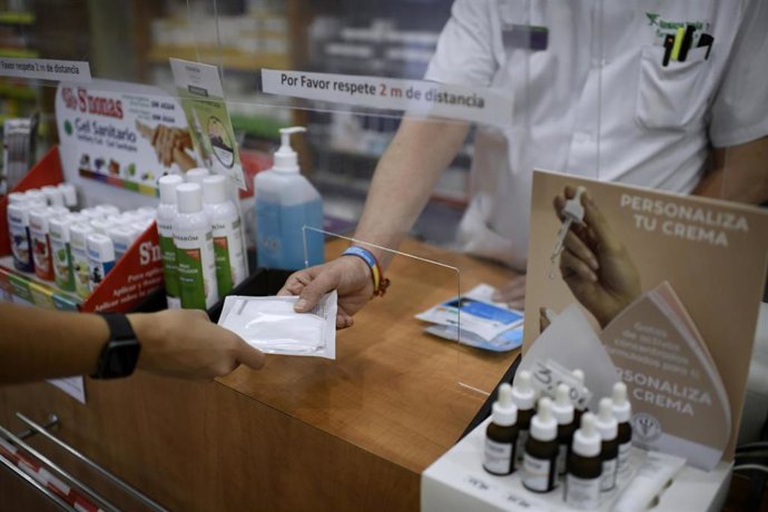 Un farmacéutico entrega a un cliente mascarillas.