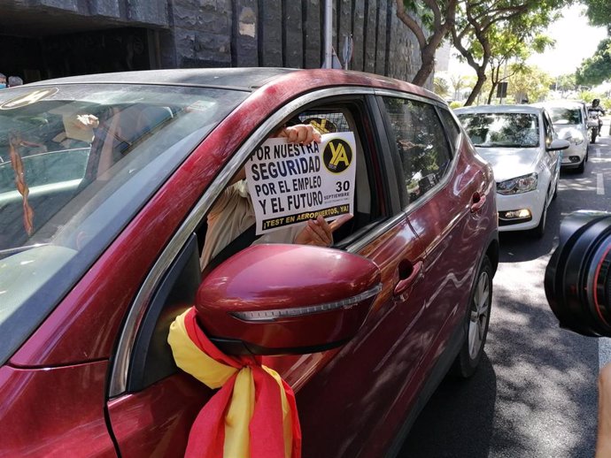 Uno de los vehículos de la caravana muestra un cartel para exigir la realización de PCR