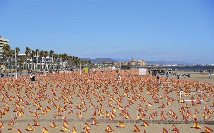 Varias personas visitan la Playa de la Patacona de Alboraya en la que se han colocado un total de 53.000 banderas de España en homenaje a los fallecidos por coronavirus, en Alboraya, Valencia (España)