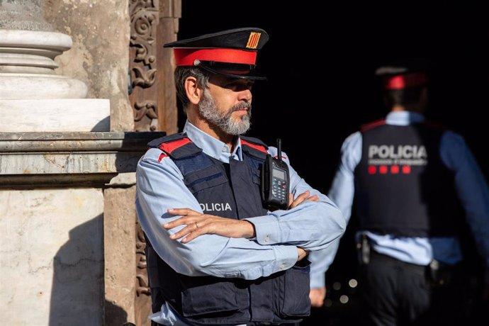 Agentes de Mossos d'esquadra observan como un hombre abuchea al diputado de Ciudadanos en el Parlament de Catalunya, Carlos Carrizosa, mientras ofrece declaraciones a los medios de comunicación.  