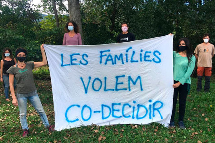 Pla general de diversos pares i mares d'alumnes de l'escola de Mieres aguantant una pancarta per demanar decidir conjuntament les mesures de les escoles el 30 de setembre de 2020 (Horitzontal)