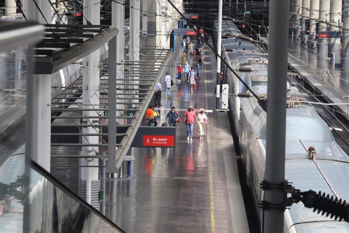 Imagen de un tren detenido en un andén en la estación Madrid-Puerta de Atocha y pasajeros caminando durante el viernes previo al primer fin de semana tras el estado de alarma, en Madrid (España), a 26 de junio de 2020.